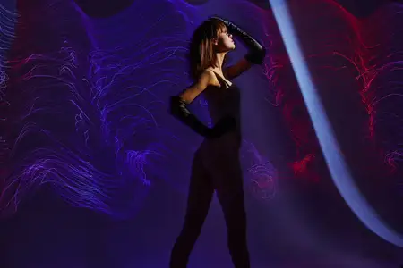 Молодая привлекательная девушка позирует на цветном фоне в окружении неоновых линий