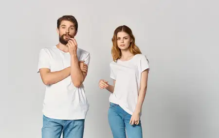 Мужчина и женщина в джинсах и футболках на светлом фоне жестикулируют руками