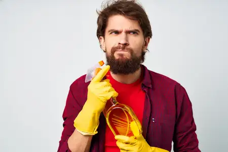 Бородатый мужчина с моющим средством в резиновых перчатках, оказывающий услуги, обрезной вид, профессионально
