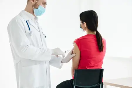 Мужчина-врач со шприцем в руках делает инъекцию в плечо пациента