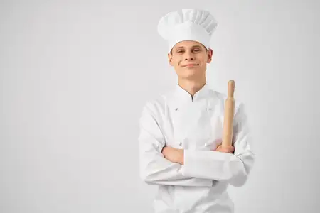 Мужчина в поварской форме готовит на кухне ресторана