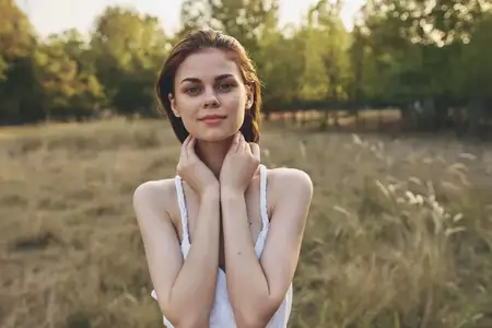 Счастливая женщина наслаждается жизнью на лугу среди травы и деревьев во время летнего отпуска