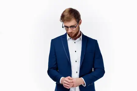 Мужчина в классическом костюме, очках и синем пиджаке на светлом фоне