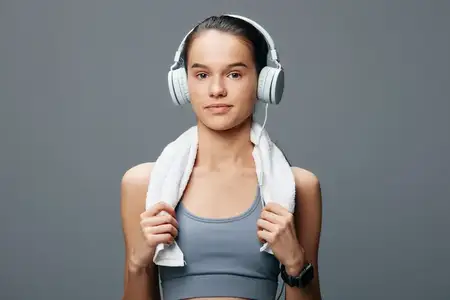 Спортивная женщина, образ, вдохновлённый спортом, с фитнес-одеждой, наушниками и полотенцем для занятий в тренажёрном зале
