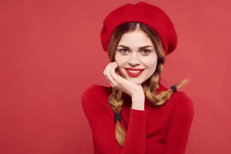 Симпатичная женщина с косичками, весёлая, с красными губами на роскошном красном фоне