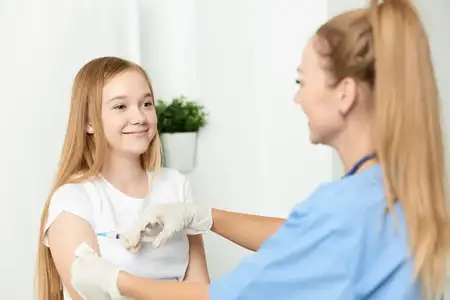 Женщина-врач делает девочке укол в руку, вакцинация