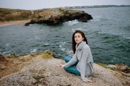 Женщина на пляже в облачную погоду, каменистое побережье, туристический образ жизни