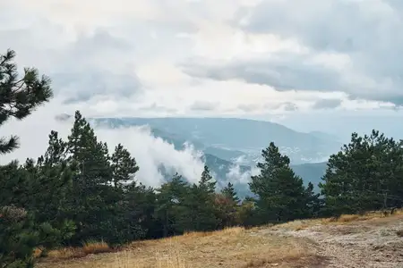 Живописный горный пейзаж с облаками на вершине холма, безмятежный ландшафт для путешествий и знакомства с природой