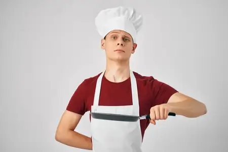 Мужчина-повар на кухне занимается приготовлением пищи в ресторане