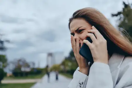 Молодая бизнес-леди выражает беспокойство во время разговора по телефону в городском парке, воплощая трудности современного баланса между работой и личной жизнью