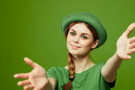 Счастливая женщина в зелёной футболке и шляпе с трилистником празднует День Святого Патрика
