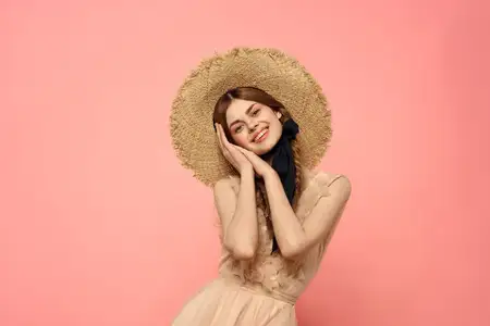 Модная женщина в платье и шляпе с чёрной лентой на розовом фоне, кадрированное изображение модели, эмоции, веселье