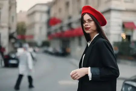 Портрет модной женщины на улице на фоне города в стильной одежде, с красными губами и красным беретом