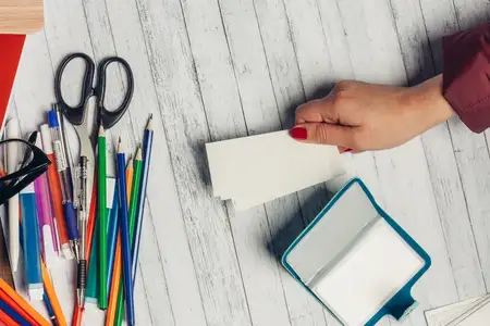 Офисный стол, отзывы и женская рука с канцелярскими принадлежностями: карандашами, ножницами, маркерами
