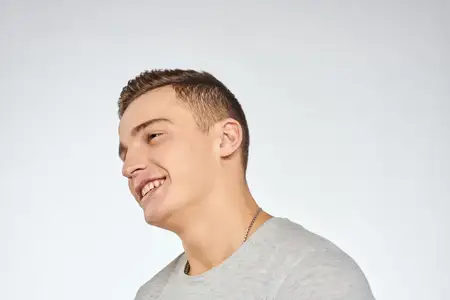 Эмоциональный жизнерадостный мужчина в серой футболке жестикулирует руками в студии