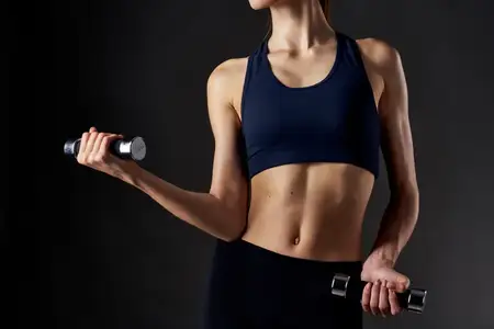 Спортивная стройная женщина с гантелями в руках, образ жизни