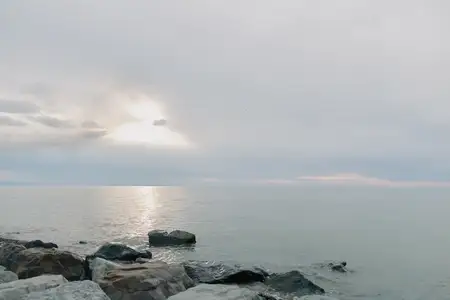 Безмятежный вид на океан с камнями вдоль берега и облачным небом во время раннего утреннего восхода солнца