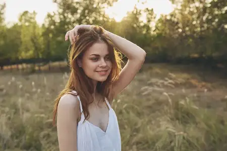Жизнерадостная женщина наслаждается свободой на природе, гуляя по полю и вдыхая свежий воздух