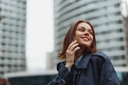 Портрет жизнерадостной женщины в повседневной одежде на фоне современных зданий
