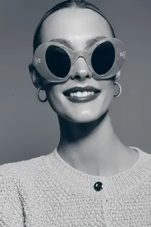 Счастливая светлокожая женщина европеоидной расы в солнцезащитных очках и вязаном свитере