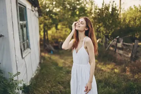 Женщина в белом платье веселится на улице в деревне