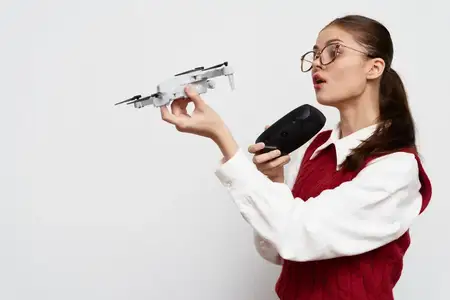 Молодая женщина демонстрирует небольшой дрон, одновременно говоря в портативную колонку, демонстрируя свою страсть к технологиям в минималистичной обстановке