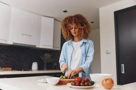 Молодая афроамериканка готовит вкусный домашний обед у себя на кухне