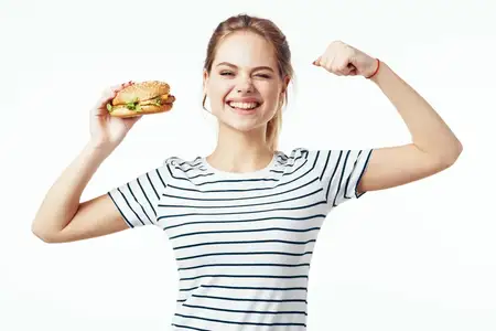 Женщина в полосатой футболке ест фастфуд, перекус, вредная еда