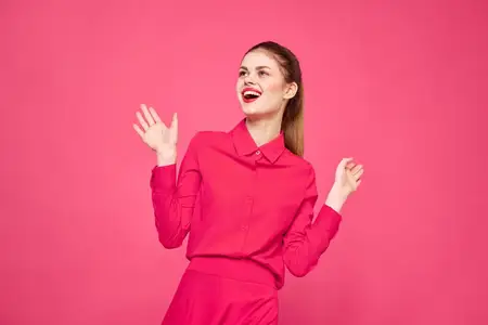 Женщина на розовом фоне в модной одежде, с ярким макияжем и прической