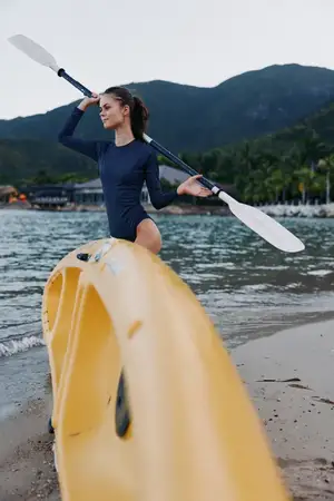 Непринужденная outdoor-спортивная сцена с уравновешенным спортсменом в купальнике, захватывающим прибрежным пейзажем, спокойной водой и ощущением свободы, силы и приключений