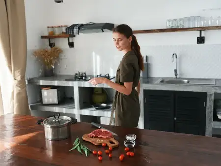 Женщина дома на кухне готовит еду, используя мясо и овощи