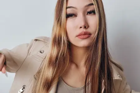 Женская модель со светло-каштановыми волосами и стильной бежевой курткой позирует для портрета