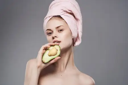 Красивая женщина с обнажёнными плечами после душа, в руке экзотический фрукт, кадрированный вид
