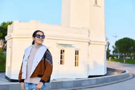 Уличное модное изображение: стильная женщина рядом с чистой белой конструкцией