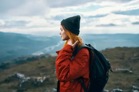 Женщина путешествует в горах, пейзаж, рюкзак, красная куртка и шляпа, модель