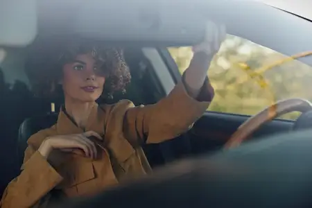Портрет женщины в автомобиле в дневное время в стиле лайфстайл, с эффектом ретро-пленки, искренний момент, стильный гардероб, тонкое свечение, акцент на руках на руле и взгляде, приглашающее…