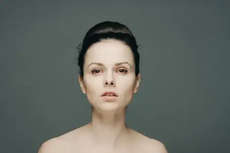 Красивая женщина с обнаженными плечами, чистой кожей и собранными волосами, передающая эмоции
