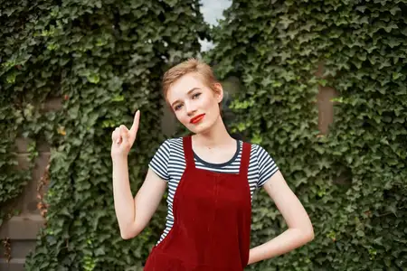 Женщина с красными губами на открытом воздухе на фоне кустарника