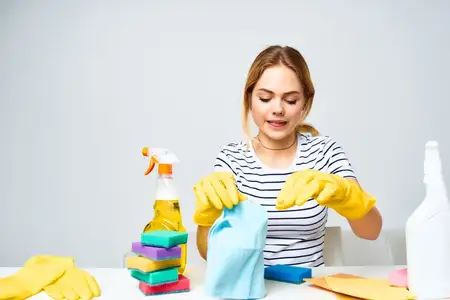 Уборщица сидит за столом, оказывая услуги по уборке дома
