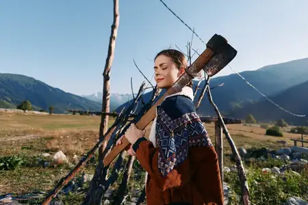 Женщина-дровосек несет топор на плече в сельской местности и горах