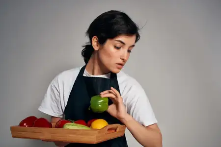 Повар в черном фартуке на изолированном фоне с овощами и свежей едой