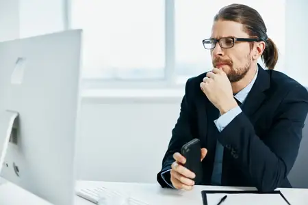 Мужчина в костюме в офисе жестикулирует руками перед компьютером