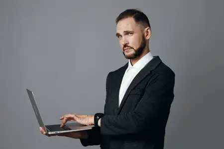 Сцена изображает опытного профессионала за работой, демонстрирующего решительные эмоции и сильную вовлеченность при работе с ноутбуком на ярком цветном фоне