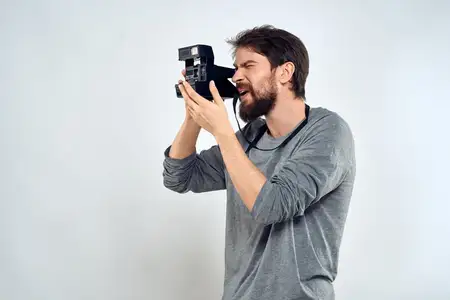 Мужчина-фотограф с профессиональной камерой работает в студии