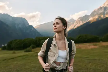 Портрет женщины-туристки в альпийском пейзаже, исследующей тропы, чувствующей себя свободной и уверенной среди гор, лугов и голубого неба