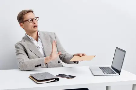 Удивленный мужчина работает с ноутбуком, держа в руках кредитную карту, что иллюстрирует концепцию онлайн-банкинга с технологией кибербезопасности и цифровой защиты на белом студийном фоне…