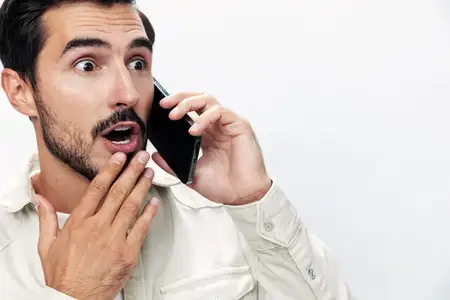 Крупный план портрета мужчины, который разговаривает по телефону с удивлением и страхом на белом изолированном фоне