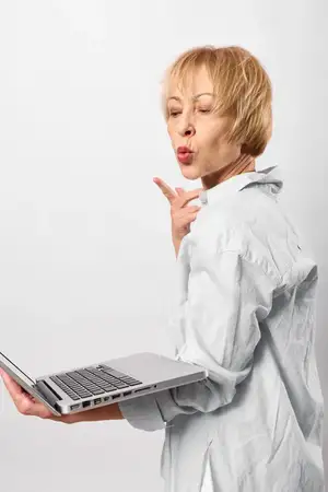 Женщина с ноутбуком, коммуникация, бизнес, офис, технологии, студийный портрет, удивлённый бизнес-сотрудник в белой блузке держит ноутбук и говорит с жестом руки в студийном пространстве