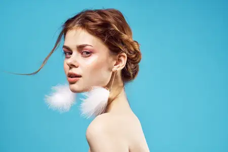 Сексуальная женщина с обнаженными плечами, ярким макияжем, в модном образе на роскошном синем фоне