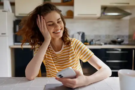 Непринужденный портрет молодой женщины на современной кухне, наслаждающейся моментом отдыха и света